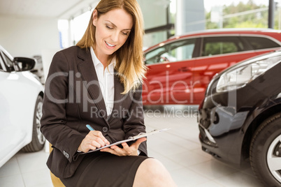 Smiling saleswoman writing on a clipboard