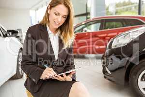 Smiling saleswoman writing on a clipboard