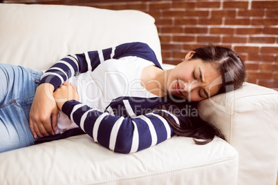Asian woman lying on the couch with cramps
