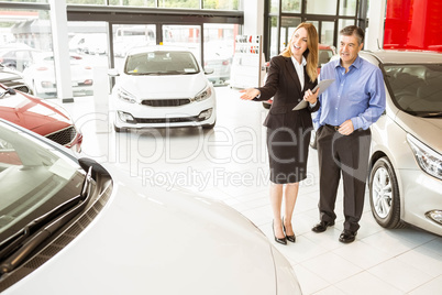 Smiling businesswoman showing car to customer