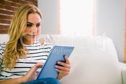 Pretty blonde using tablet on couch