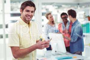 Creative businessman using smartphone in front of colleagues