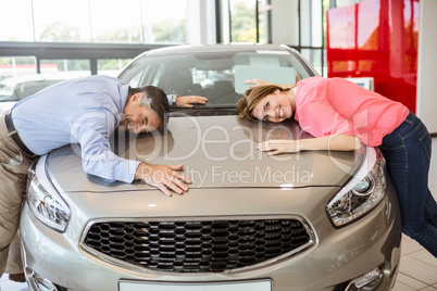 Casual smiling couple hugging their new car
