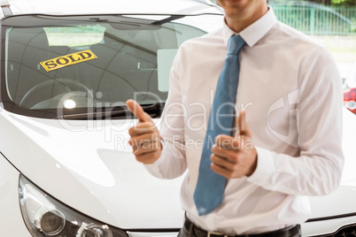 Smiling businessman standing while giving thumbs up