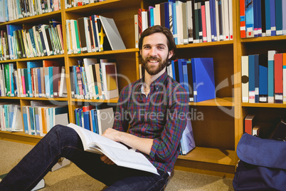 Student reading book in library on floor