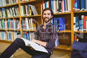 Student reading book in library on floor