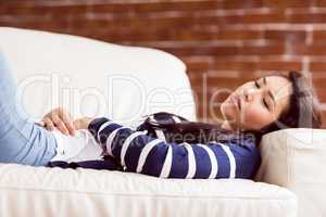 Asian woman lying on the couch with cramps