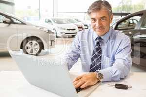 Smiling salesman behind his desk