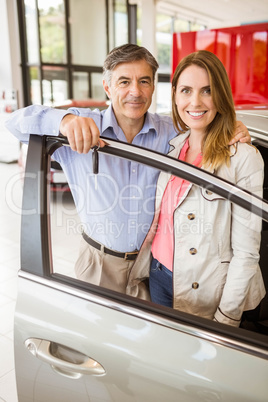 Smiling couple leaning on car