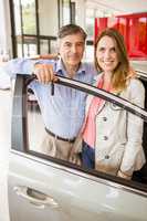 Smiling couple leaning on car