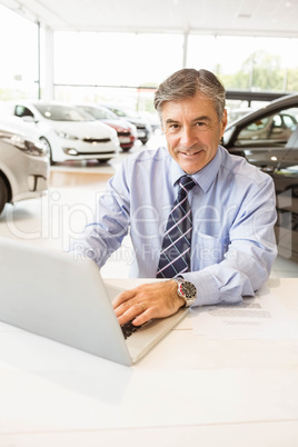 Smiling salesman behind his desk