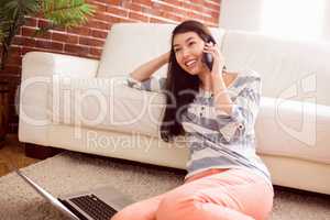 Asian woman using phone on floor