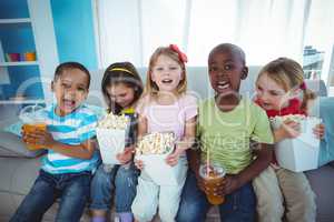 Happy kids enjoying popcorn and drinks while sitting