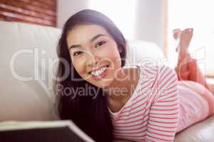 Smiling asian woman on couch reading