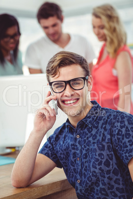 Smiling creative businessman working near co workers