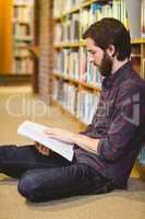 Student reading book in library on floor