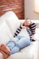 Asian woman lying on the couch listening to music