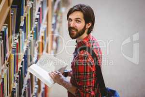 Student picking a book from shelf in library