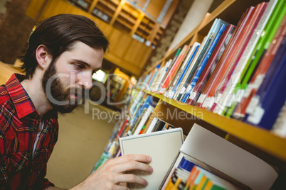 Happy student picking book in library