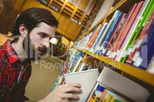 Happy student picking book in library