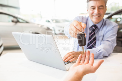 Smiling salesman holding a customer car key