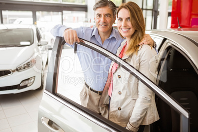 Smiling couple leaning on car