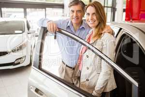 Smiling couple leaning on car