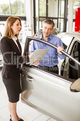 Smiling businessman undersign a car contract