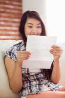 Asian woman on the couch reading letter