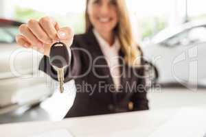 Smiling saleswoman holding car key