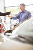 Saleswoman giving car keys while shaking hand of a client