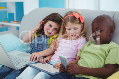 Happy kids sitting together with a tablet and laptop and phone