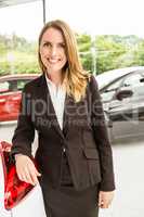 Smiling saleswoman standing against a car