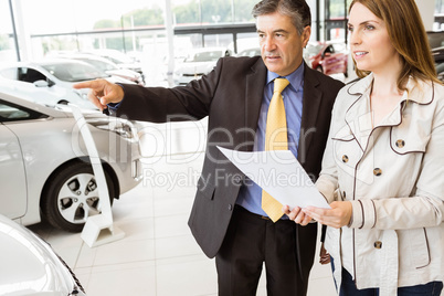 Salesman pointing a car to a client