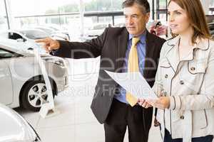 Salesman pointing a car to a client