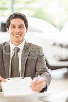 Smiling salesman holding a contract and a pen