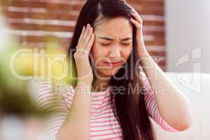 Asian woman getting headache on couch