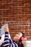 Asian woman lying on the couch listening to music