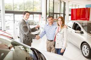 Salesman giving car key to a couple
