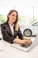 Smiling saleswoman typing on her laptop