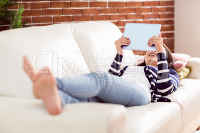 Asian woman lying on the couch using tablet