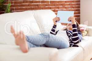 Asian woman lying on the couch using tablet