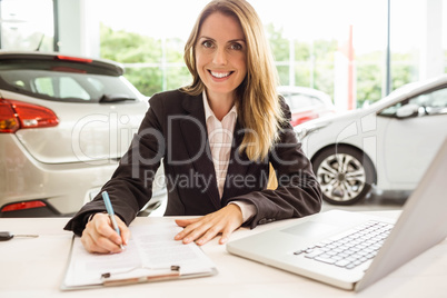 Smiling saleswoman writing on a clipboard
