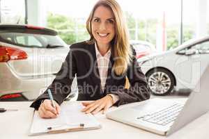 Smiling saleswoman writing on a clipboard