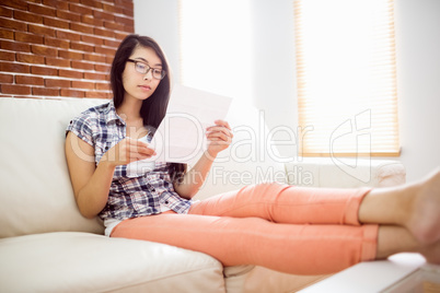 Asian woman on the couch reading letter