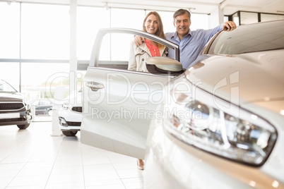 Smiling couple leaning on car