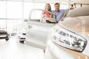 Smiling couple leaning on car