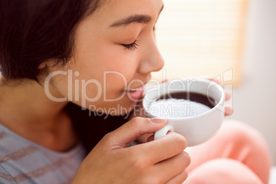 Asian woman relaxing on couch with coffee