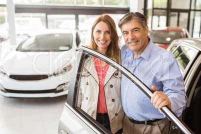 Smiling couple leaning on car