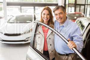 Smiling couple leaning on car